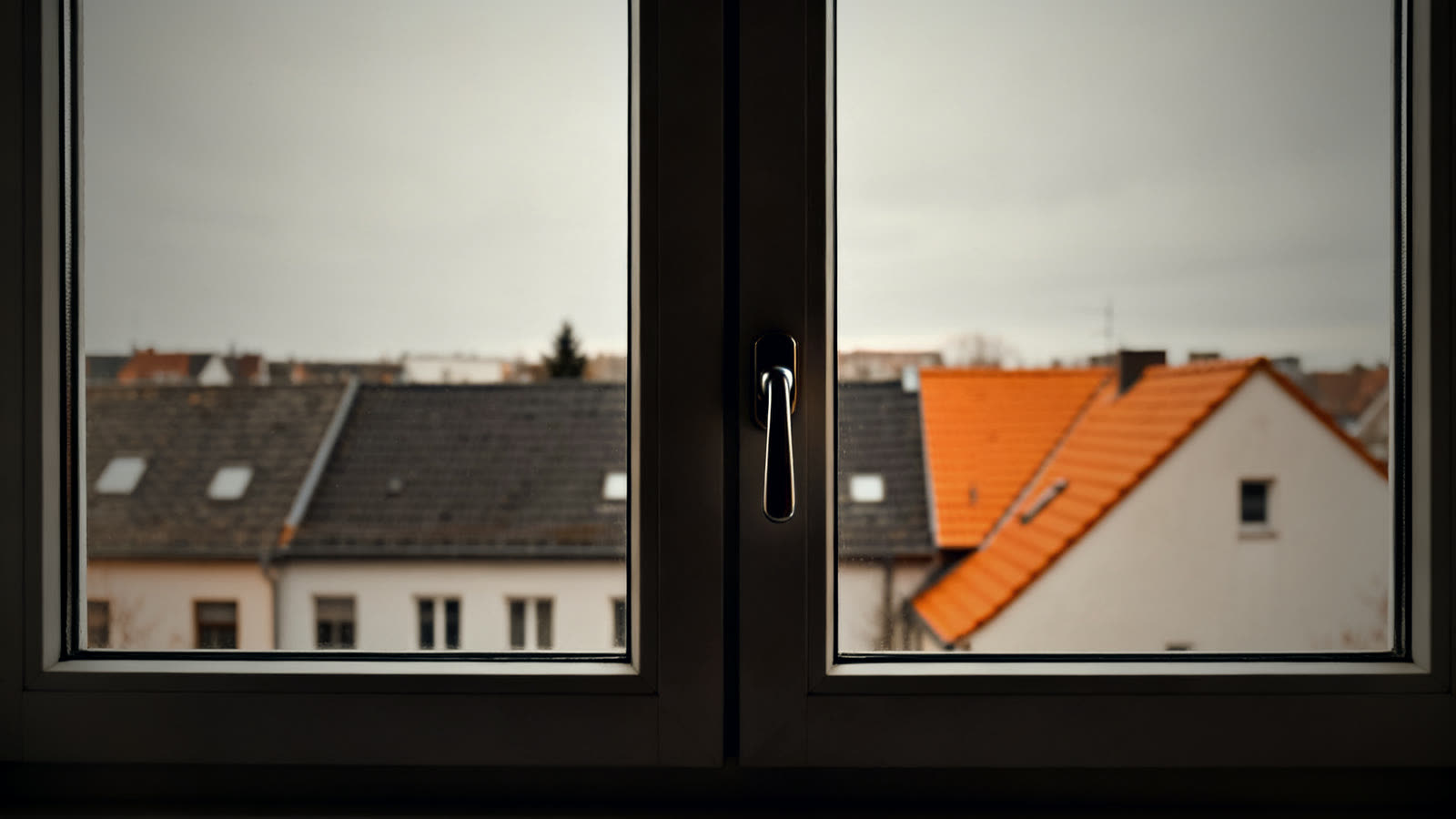 Geschlossenes Fenster mit Blick auf Dächer, Symbol für Schutz bei einer Gefahrstoff-Warnung