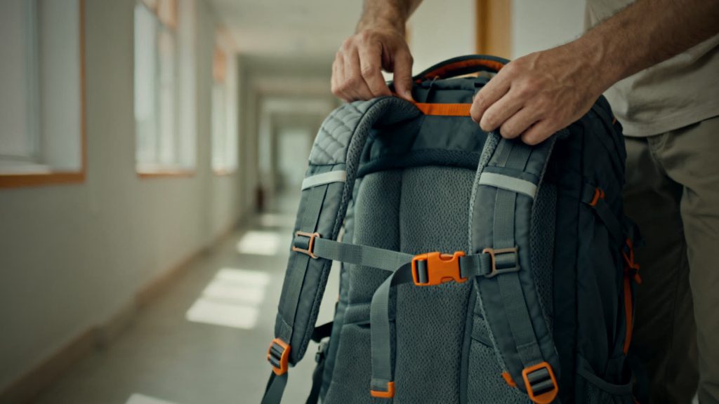 Hände stellen das Tragesystem eines Notfallrucksacks mit Hüftgurt und Schultergurten ein