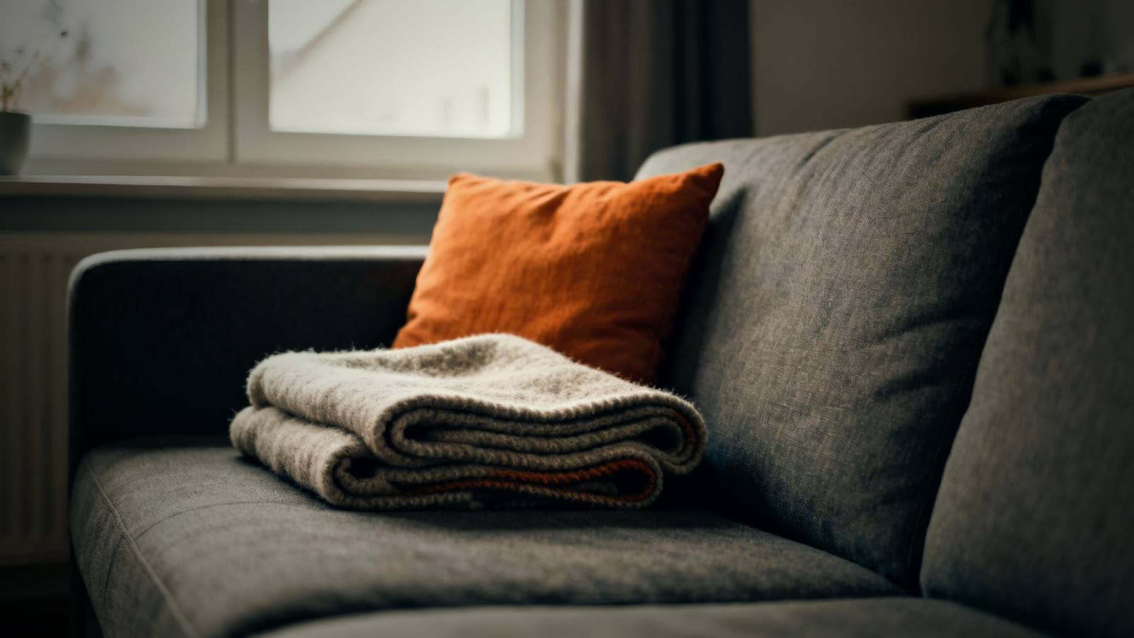 Gefaltete Wolldecke auf einem Sofa als Hilfe, wenn man eine Unterkühlung erkennen und behandeln muss