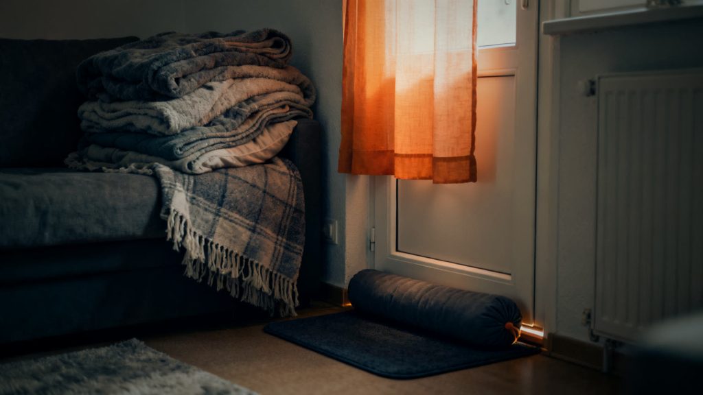 Habitación caliente acogedora, con mantas y un burlete para puertas, como refugio ante un fallo de la calefacción